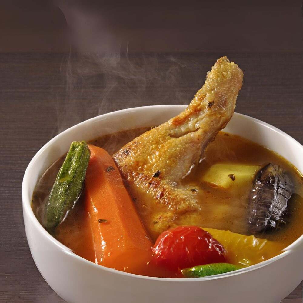 北海道スープカレー画像。大きな鶏モモ肉と大きくカットされた野菜のカレー。
